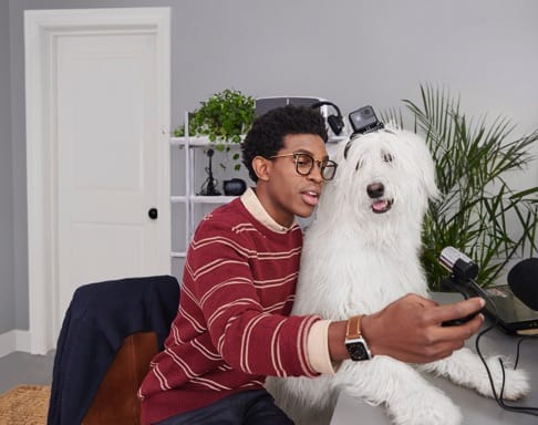 A young man is taking a picture of himself and his dog. 